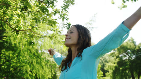 woman standing with arms outstretched in the park