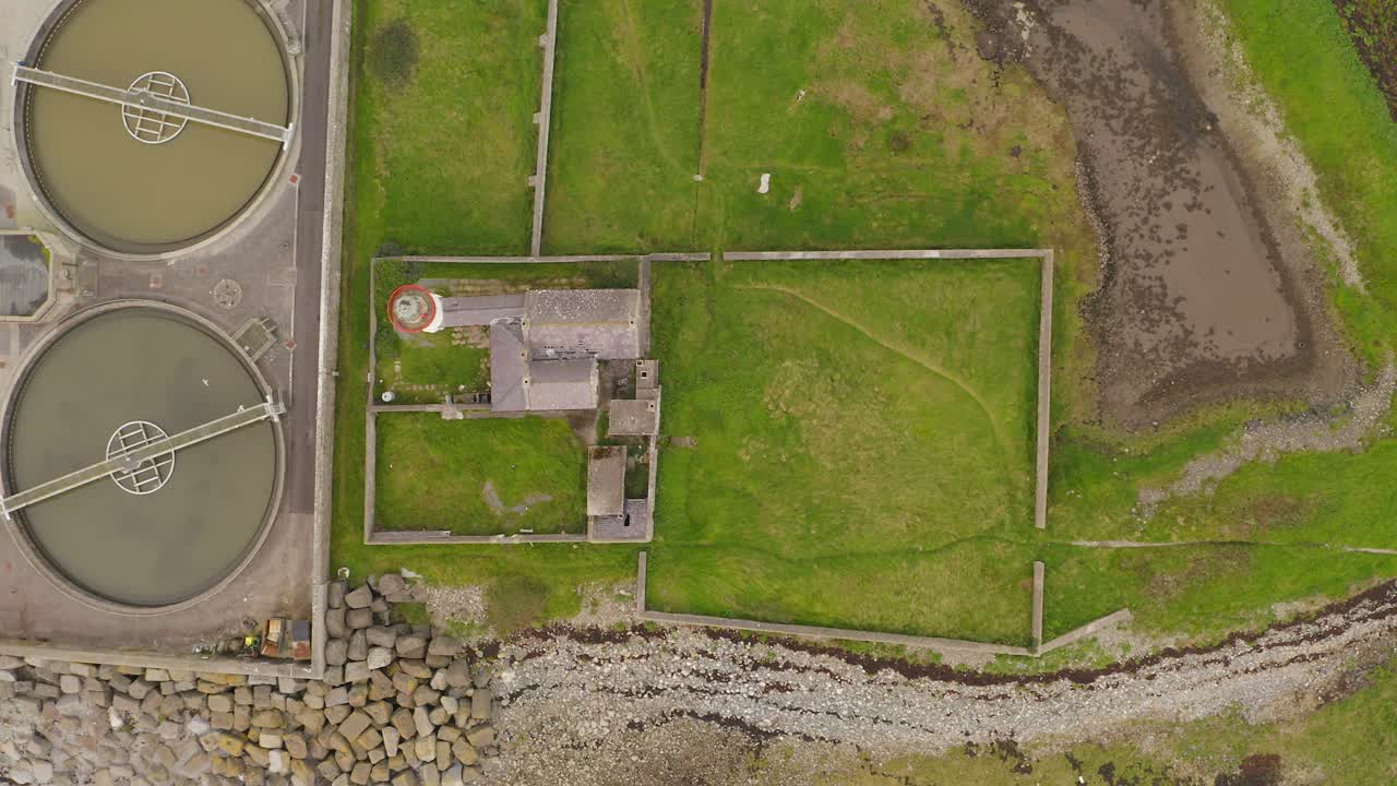 старый маяк рядом с очистной станцией сточных вод на травяном острове, воздушный сверху вниз