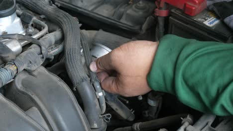 a car mechanic working on an old engine fixing a throttle valve using his hands