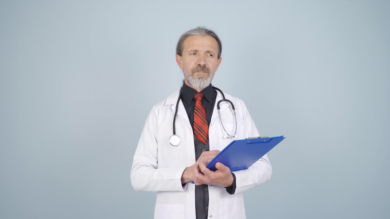 The doctor looks at the camera with a plain expression.