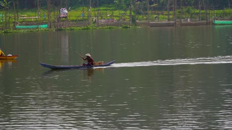 Cámara-Lenta---Pescador-Tradicional-Remando-En-Un-Bote-De-Madera-A-Través-Del-Lago---Lago-Rawa-Pening,-Indonesia