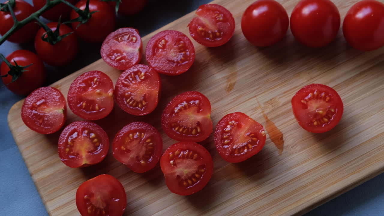 Top view of man hands cutting cherry tomatoes on the cutting board.
