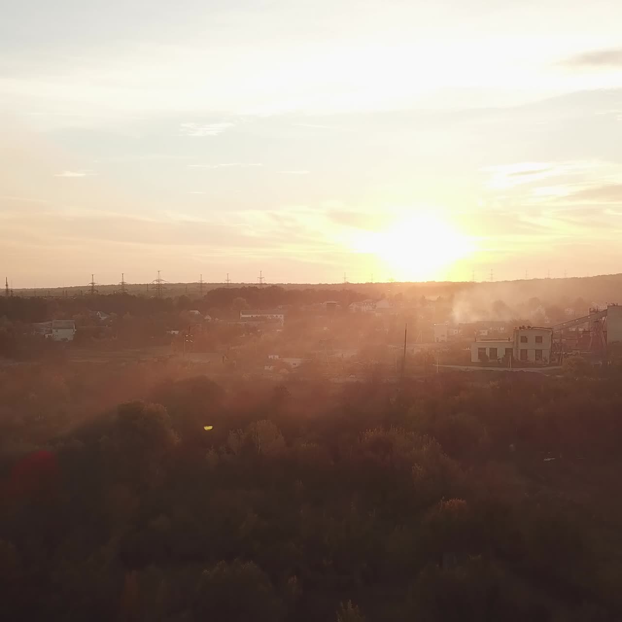 smoke from the fire are soaring over the river and evening city on the background of sunset in the summer. Aerial view