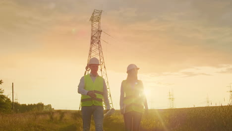 coworking engineers with tablets on solar plant. adult men and women in hardhats using tablets while standing outdoors on transformer platform. transportation of clean energy. wind energy delivery