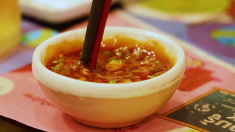 chopsticks stirring sauce in a small bowl