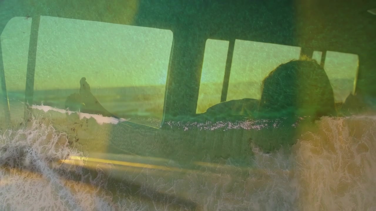 Donna appoggiata al sedile, con un bagliore solare che crea una sovrapposizione di onde che sale sopra il finestrino, oscurando il profilo per un film.
