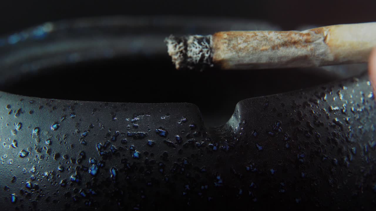un primer plano macro de residuos de ceniza de un cigarrillo en un cenicero de piedra negra, video de 4k en cámara lenta, humo blanco 2