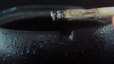 a macro close up shot of ash residue from a cigarette in a black stone ashtray, slow motion 4k video, white smoke 2