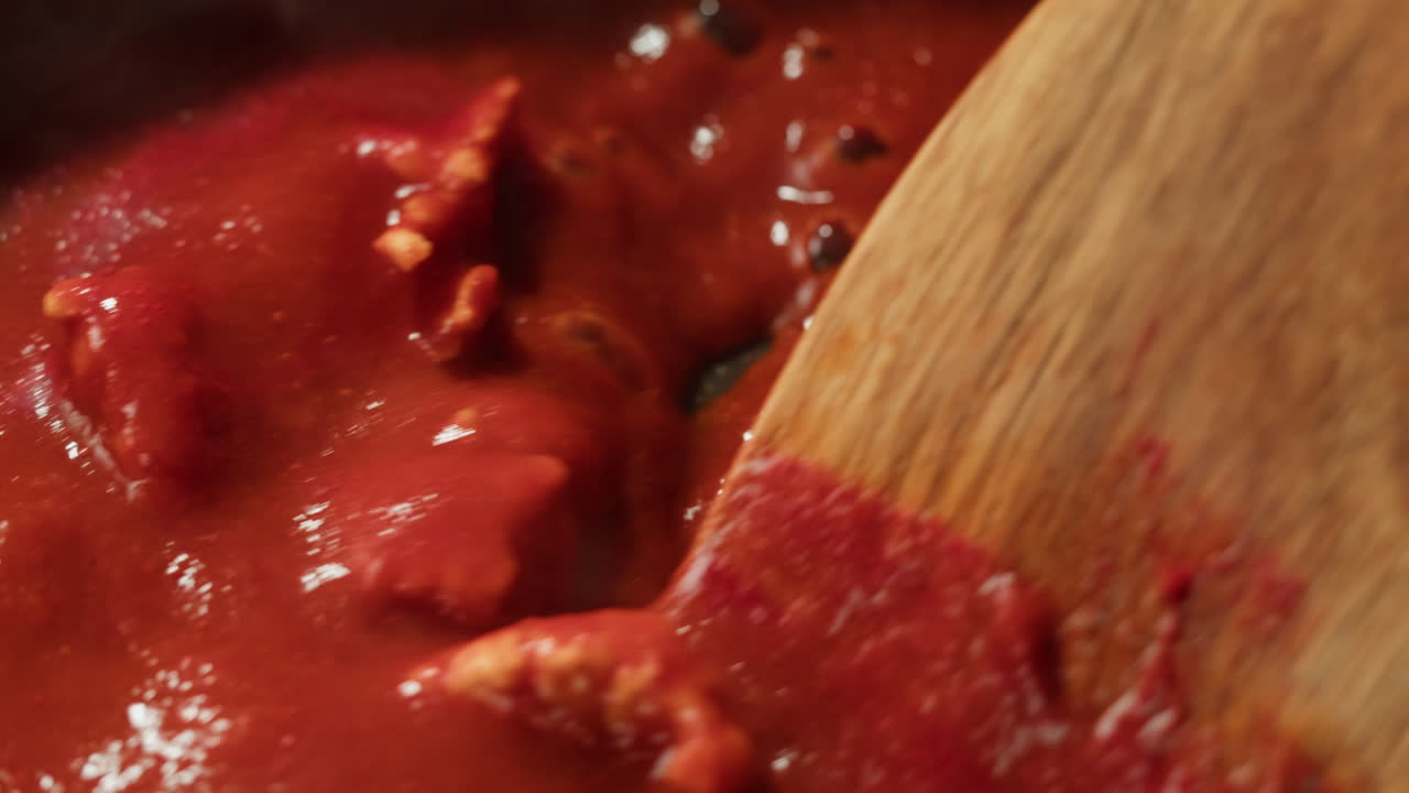 Chicken in tomato sauce is boiling on a frying pan with spices. Cooking tomato sauce curry with chicken fillet. Traditional Italian Mexican Asian dish. High quality studio shot for cafe, restaurant close up.