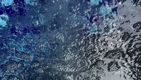 burbujas de aire en el jacuzzi al aire libre contra azulejos azules.