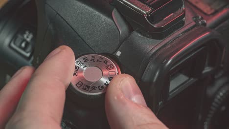 man turning canon dslr camera settings mode dial wheel to the m manual mode from the full automatic mode