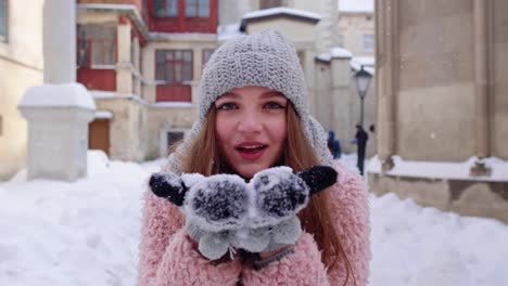 Junge-Reisende-Touristin-Zeigt-Schnee-In-Den-Händen,-Handflächen-Zur-Kamera-Und-Bläst-Ihn-Auf-Die-Stadtstraße