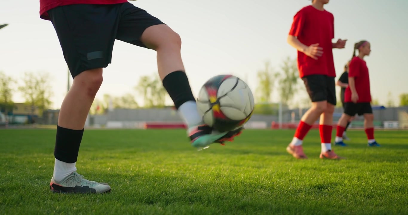 Giovani calciatori si allenano e palleggiano su un campo verde