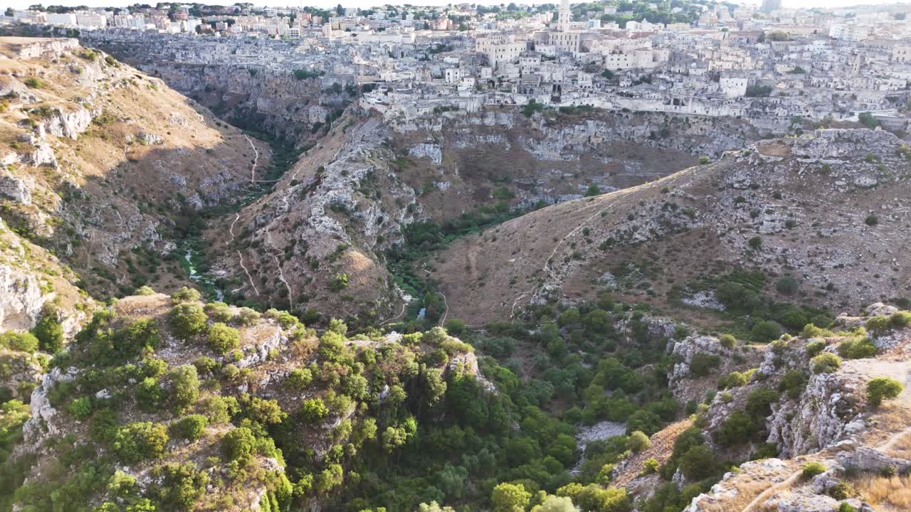 Deep valley and Matera city on sunny evening, aerial drone view