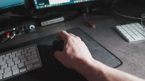 pov of a hand using a mouse at a computer workstation, with changing images on the monitor reflecting productive work