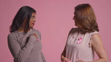 Studio-Portrait-Of-Two-Mature-Women-Proud-Of-Pink-Breast-Cancer-Awareness-Ribbons-Hugging-Against-Pink-Background-1