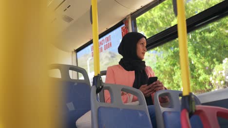 young woman wearing hijab commuting on a bus