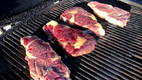 sirloin steaks grilling on a propane grill.