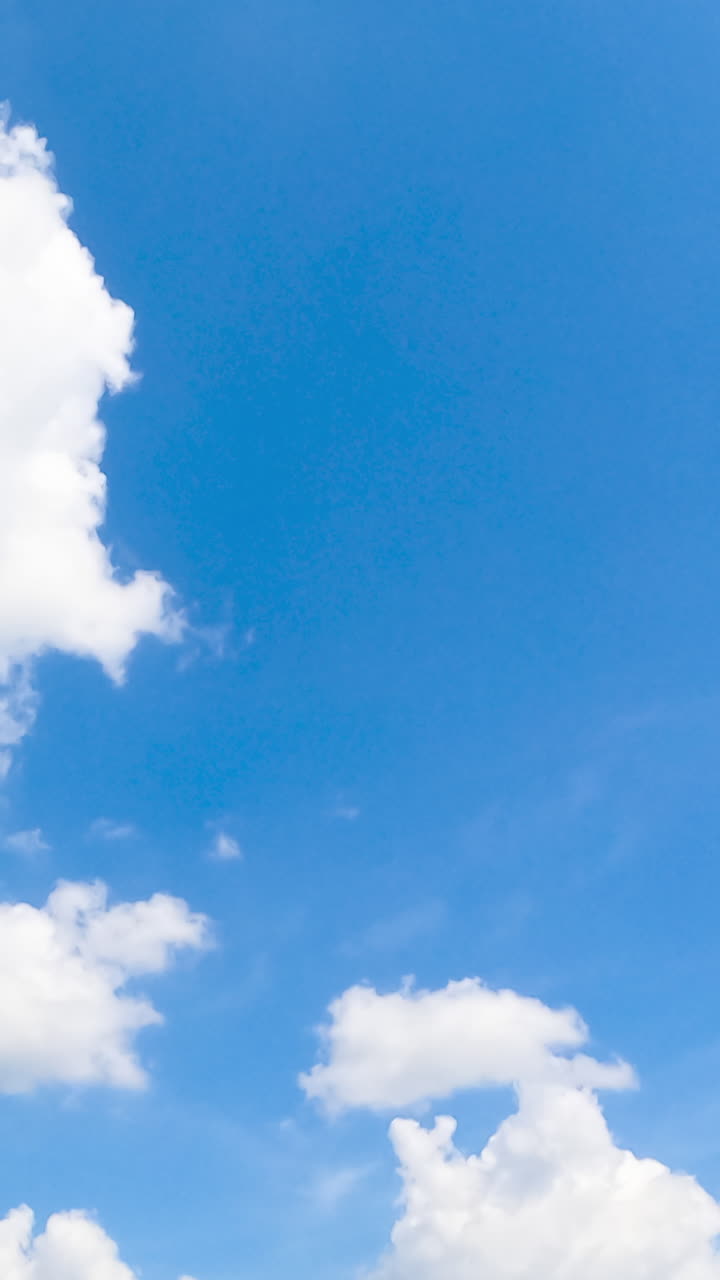 Bright summer sky with white soft clouds. Sun lighting the beautiful cloudscape. Low angle view. Timelapse. Vertical video