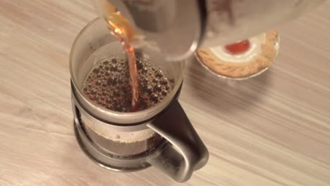 pouring fresh coffee into a pot with cherry cake