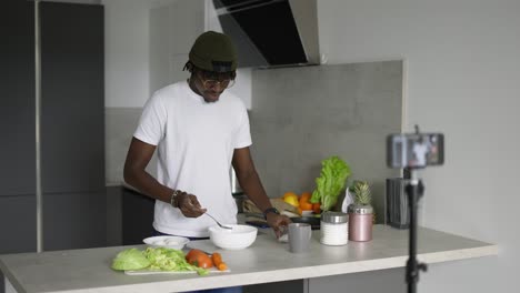 African-man-standing-in-kitchen-records-on-cell-phone-new-food-video-blog-in-the-morning,-slow-motion