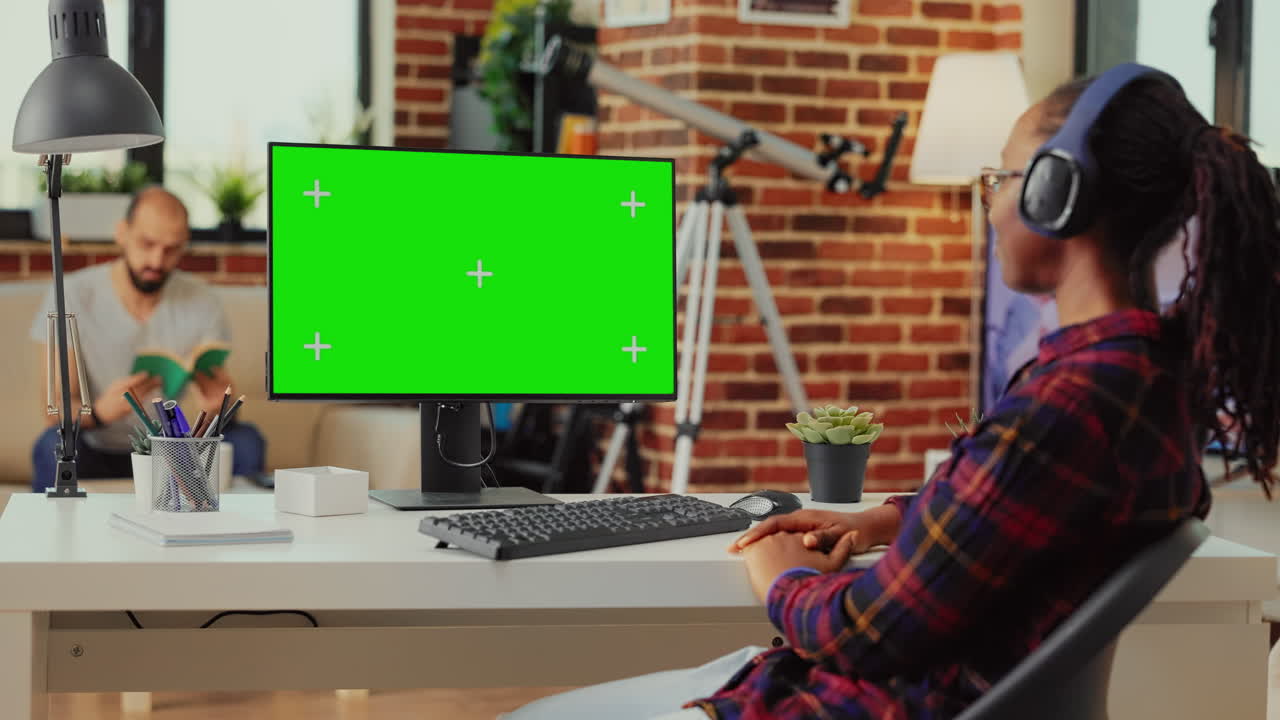 Young adult with headset looking at greenscreen display