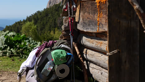 backpack and sleeping pad water trekking poles leans against wooden cabin