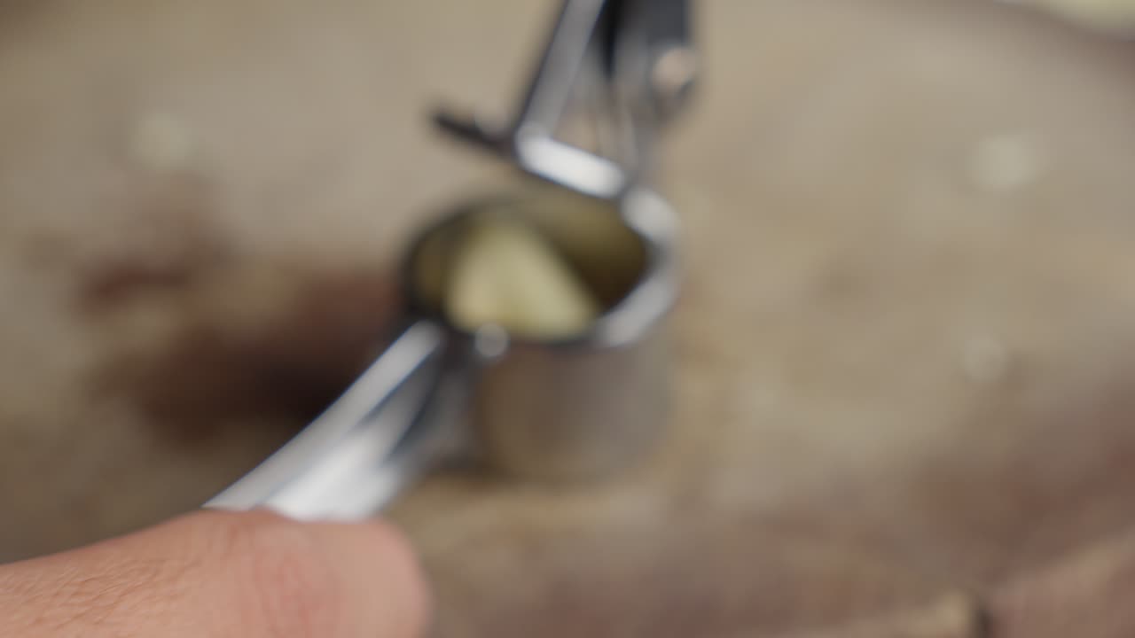 Close-up of Hands Using a Garlic Press
