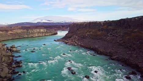 volar a través del cañón del río sobre aguas turbulentas hacia una cascada en islandia