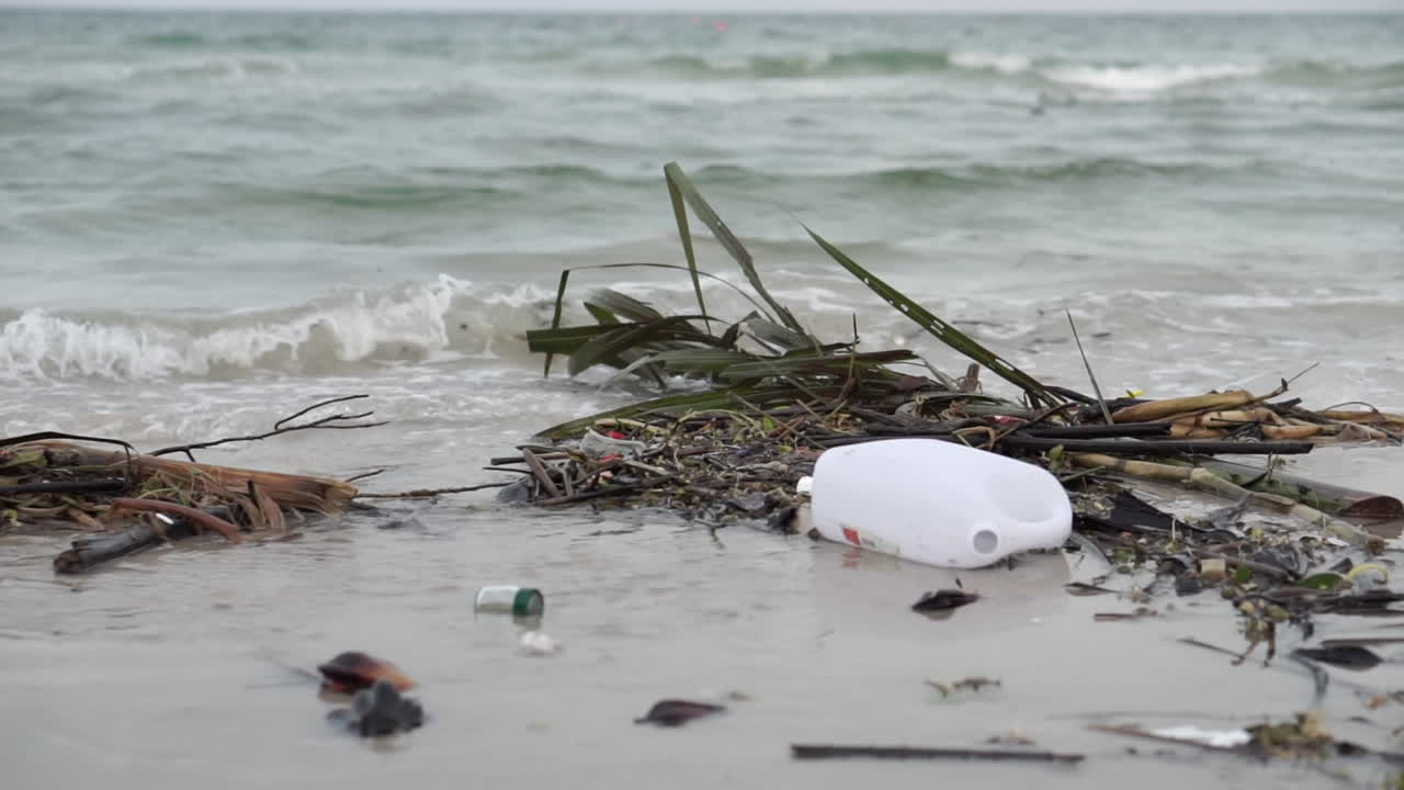 botella de plástico y residuos dejados en la arena de la playa contaminando el mar.