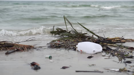 plastic bottle and waste left on the beach sand polluting the sea