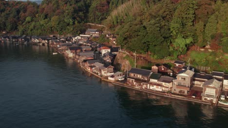 Aerial-drone-top-down-stilt-houses-in-Japanese-beach-hills-blue-sea-coastline-in-Kyoto,-kyotango-travel-destination,-traditional-wooden-architecture-of-Japan,-natural-landscape-environment