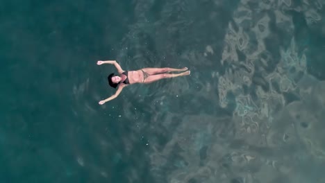 aerial drone pull out of woman swimming in the ocean