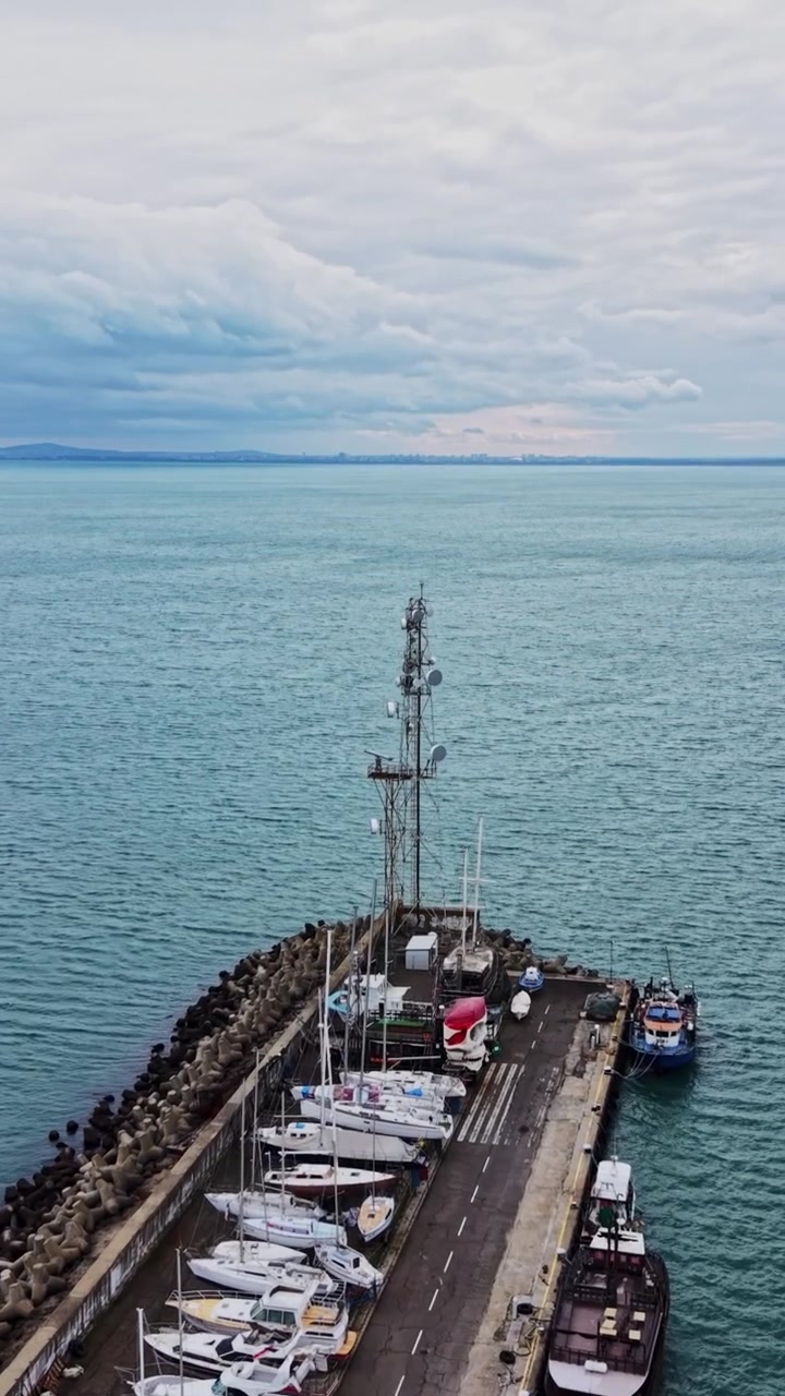Harbor view with pier and boats on water during cloudy day