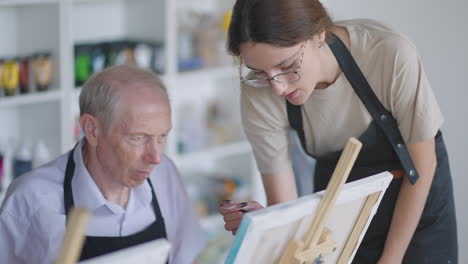 side view of a happy senior people smiling while drawing as a recreational activity or therapy in paint class together with the group of retired women and men