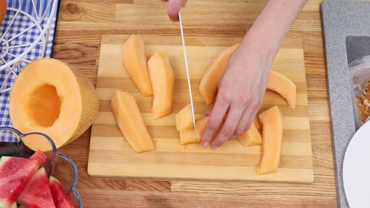 Woman cook carefully slices melon with sharp knife on board