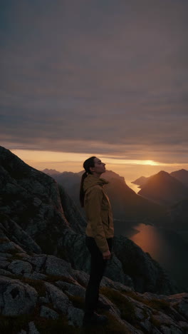 woman admiring the scenic mountain and fjord landscape at sunset