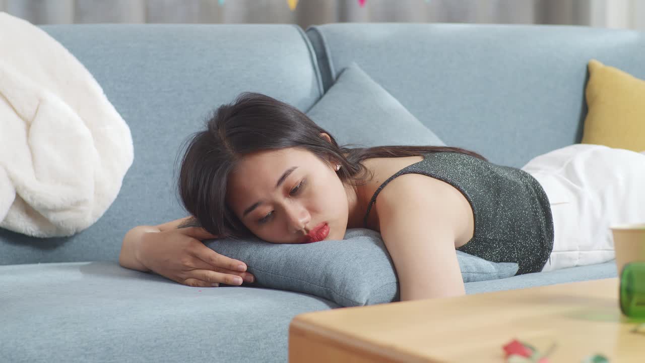 파티 후 소파에 누워 있는 슬픈 여자