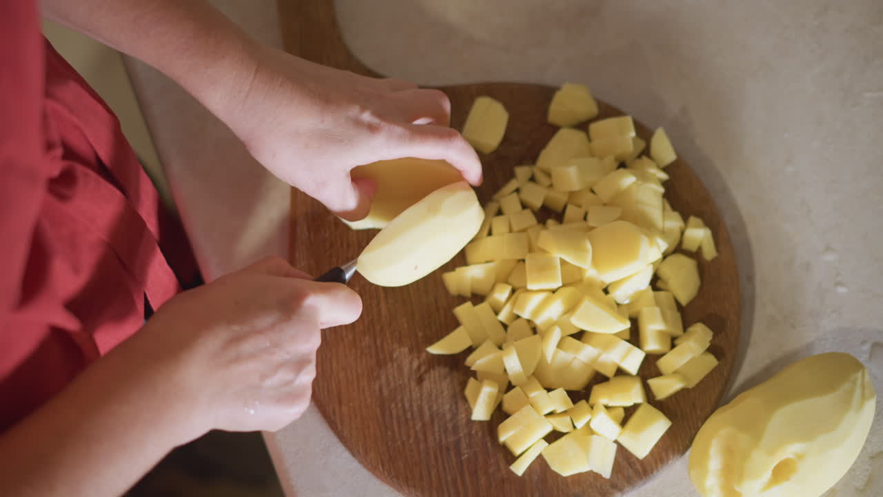 Home cook slicing potatoes on countertop fast precise strokes with stainless knife, neat pile of diced potatoes, efficient weekday routine, bright daylight, focus on speed and technique, prepping