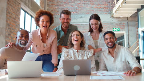 Retrato-De-Un-Equipo-De-Negocios-Multicultural-Reunido-Alrededor-De-Una-Computadora-Portátil-En-Una-Oficina-Ocupada