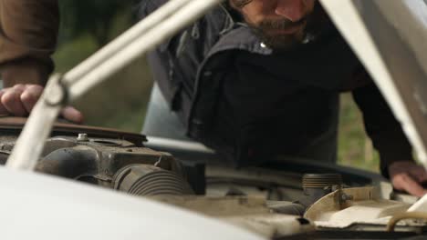 man removing cap and filling car with engine coolant servicing vehicle maintenance