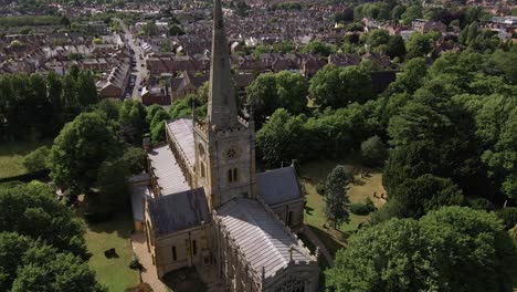 aerial view across lush green rural warwickshire countryside looking down to quaint holy trinity church