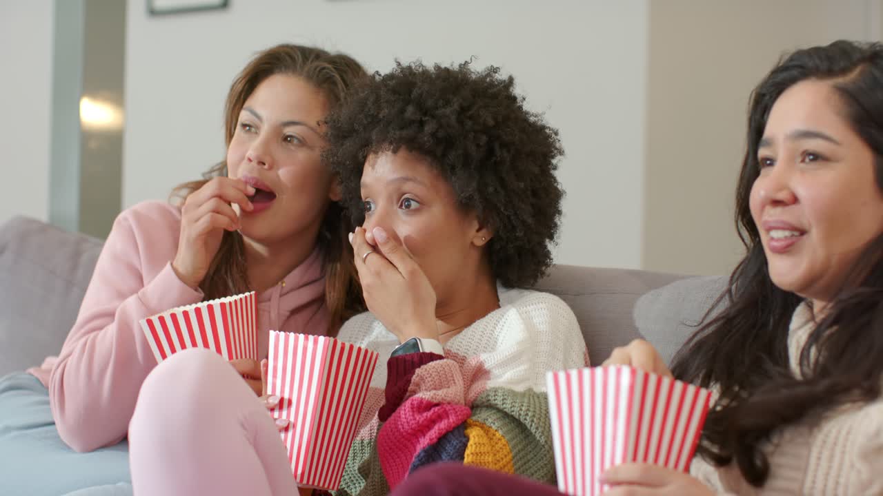 Forskellige veninder reagerer på en intens film ved at læne sig, hviske på sofaen med popcornbægre.