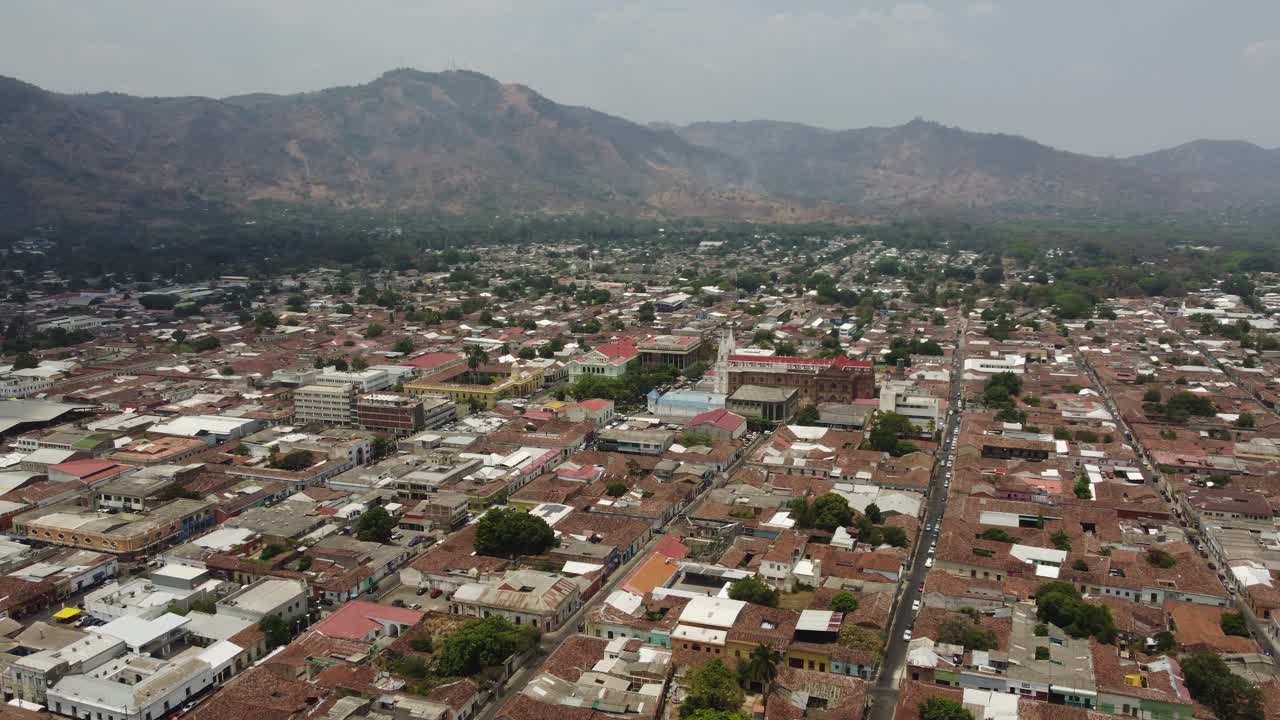 Vista aerea: città di Santa Ana con edifici bassi nelle montagne di El Salvador.