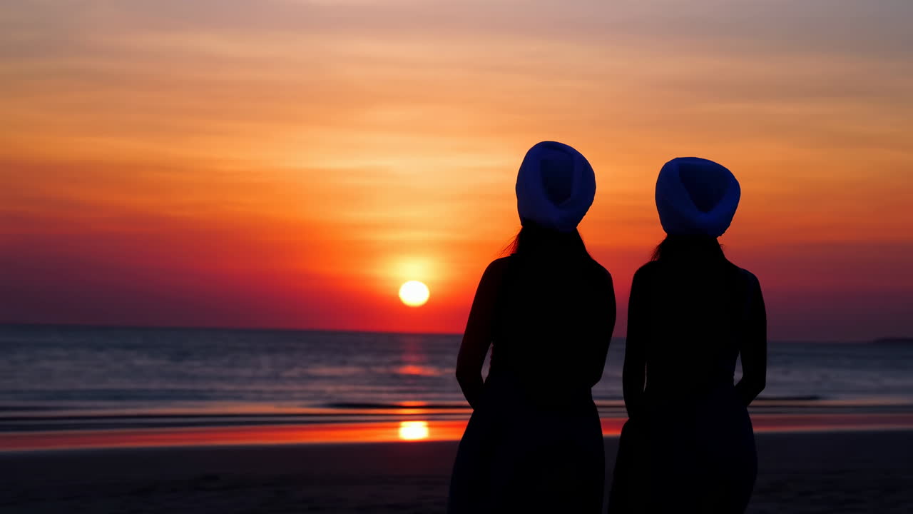 Due persone che guardano il tramonto sulla spiaggia