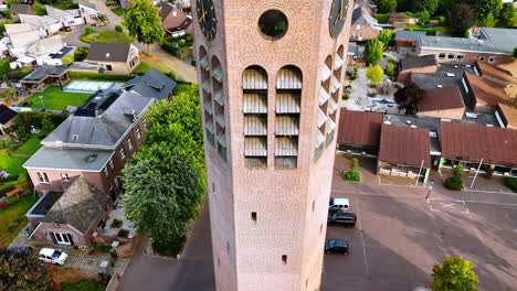rise along the brick tower with clock. church in vierlingsbeek, netherlands. green residential area at backdrop