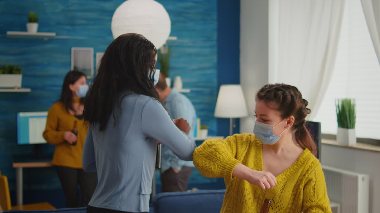 Happy multiracial friends with protective mask touching elbow