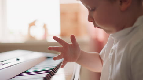 Little-boy-with-chubby-cheeks-plays-synthesizer-at-home