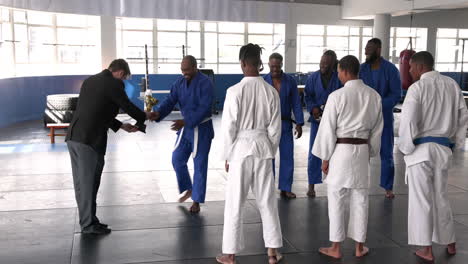 celebrating victory, judo team in blue uniforms holding trophy in dojo