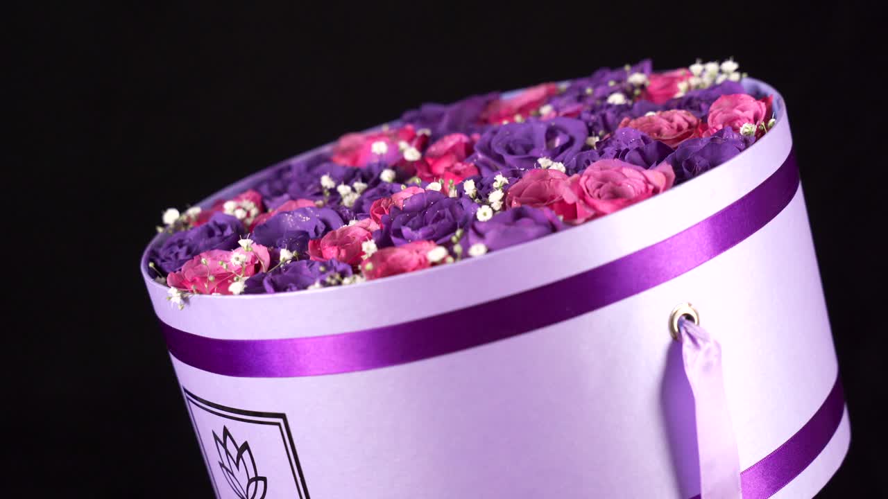 검은 배경에서 회전하는 보라색과 분홍색 장미 배열 꽃다발